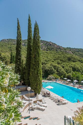 un complexe avec une piscine, des chaises et des arbres dans l'établissement Villages Clubs du Soleil - LE REVERDI, à Grimaud