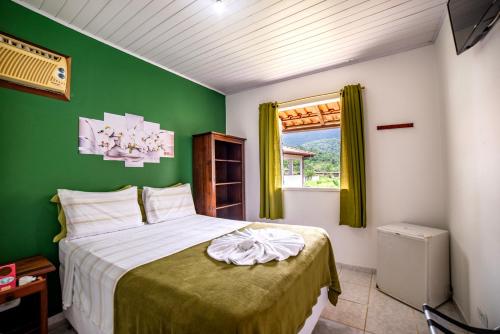 a bedroom with a bed with a green wall at Pousada Cantinho do Sossego Paraty in Paraty