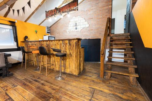a bar with stools in a room with a staircase at Keletiparty in Hajdúszoboszló