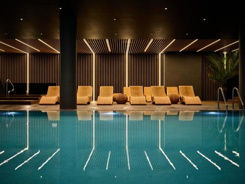 a group of chairs sitting next to a swimming pool at AC Hotel by Marriott Krakow in Kraków