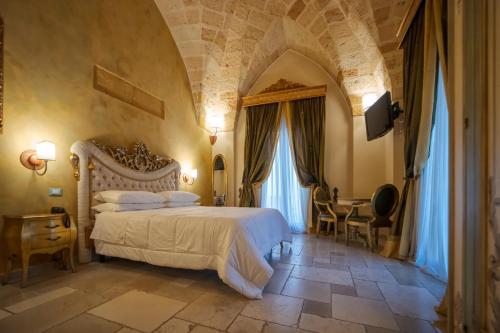 ein Schlafzimmer mit einem großen Bett und einem Tisch in der Unterkunft Kelina Charme Hotel by Cantine Due Palme in Cellino San Marco
