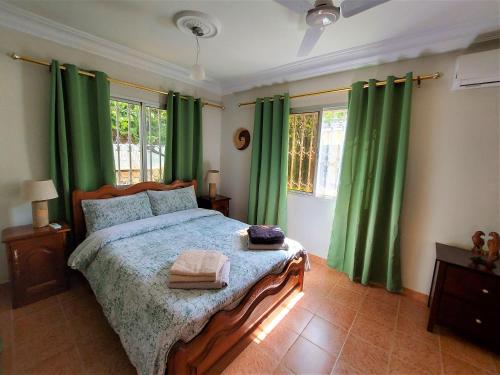 Bijilo的住宿－Bougainvillea House，一间卧室配有绿色窗帘和一张大床