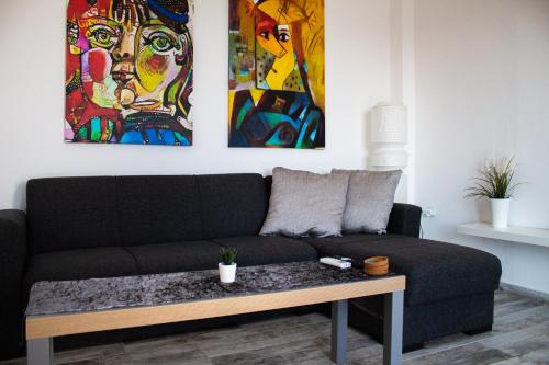 a living room with a black couch and paintings at EMVI APARTMENTS III seaview near airport in Artemida