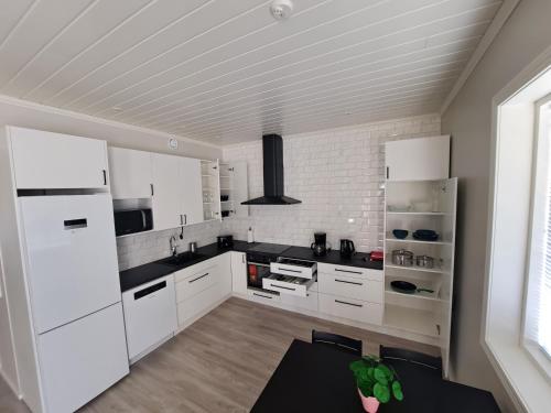eine weiße Küche mit schwarzen Arbeitsplatten und weißen Geräten in der Unterkunft ALEX - bright, stylish apartment with sauna, built in 2023 in Närpiö