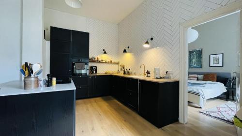 a kitchen with black cabinets and a bed in a room at ApartmentInCopenhagen Apartment 1439 in Hellerup