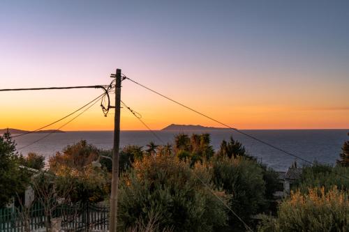 una puesta de sol sobre el océano con un poste de teléfono en Villa Ocean Breeze, en Avliótai