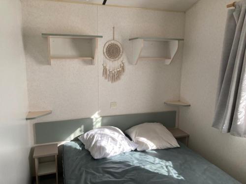 um quarto com uma cama com duas almofadas e prateleiras em Mobil home 4 personnes Plein cœur de la Vendée proche Parc du PUYDUFOU em La Boissière-de-Montaigu