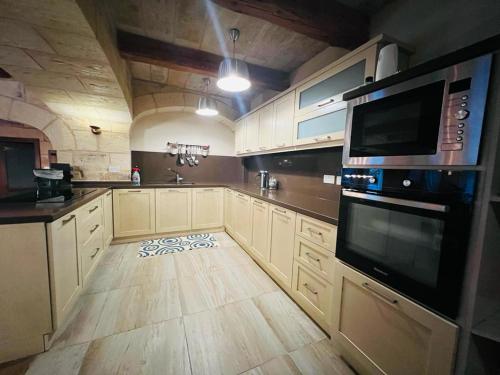 a large kitchen with white cabinets and a wooden floor at Id-dar Taz-zija Holiday Home including pool & garden in Siġġiewi