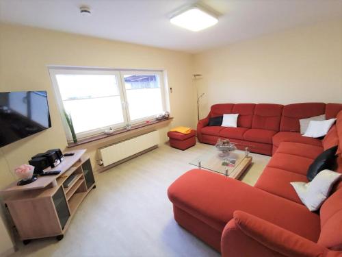 ein Wohnzimmer mit einem roten Sofa und einem TV in der Unterkunft Ferienhaus Clarissa in Allenbach