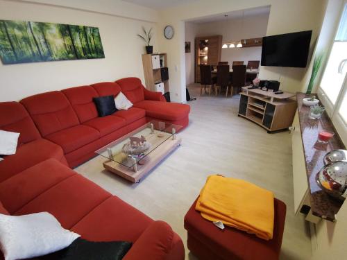 a living room with a red couch and a table at Ferienhaus Clarissa in Allenbach