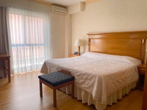 Schlafzimmer mit einem Bett mit einem Kopfteil aus Holz und einem Fenster in der Unterkunft HOTEL LAGOS INN in Lagos de Moreno