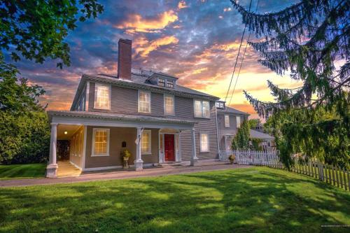 una casa con una puerta roja en el césped en The Jarvis Homestead - Historic Maine Mansion, en Ellsworth