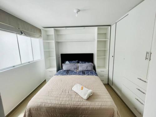 1 dormitorio con 1 cama grande con estanterías blancas en Dpto en Huanchaco a 100m de la playa, en Huanchaco