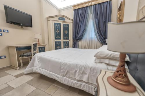 a bedroom with a bed and a tv on a wall at Kelina Charme Hotel by Cantine Due Palme in Cellino San Marco