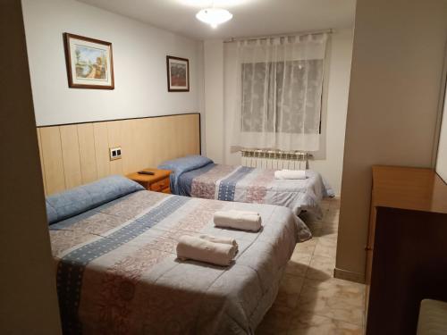 1 dormitorio con 2 camas y toallas. en Hostal Residencia Taray, en Segovia