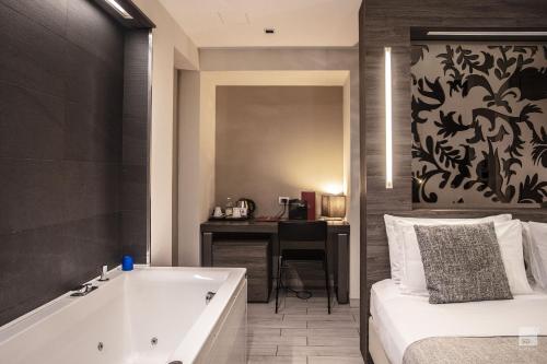 a bathroom with a tub and a bed and a desk at Hotel Diplomatic in Turin
