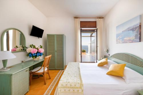 una camera d'albergo con letto, scrivania e specchio di Hotel Sporting a Vico Equense