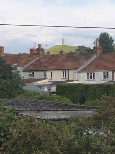 a group of houses with a green hill in the background at Phoenix Rising 2 in Glastonbury