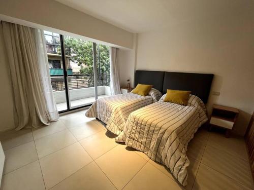 2 camas en una habitación con ventana grande en Cómodo y Moderno Departamento en Buenos Aires