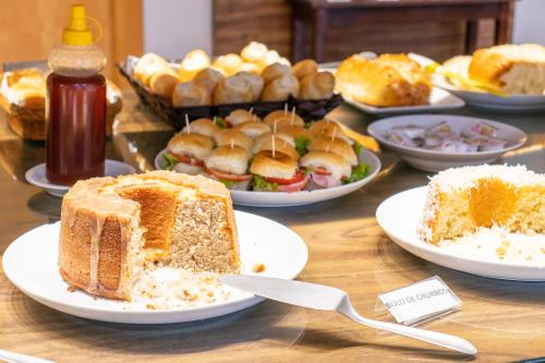 a table topped with plates of bread and other foods at Dexter Hotel - Volta Redonda in Volta Redonda