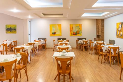 un comedor con mesas, sillas y pinturas en Dexter Hotel - Volta Redonda, en Volta Redonda