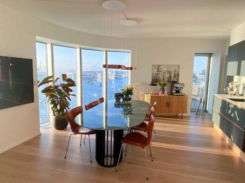 uma sala de jantar com uma mesa de vidro e cadeiras em Amazing sea view apartment em Aarhus