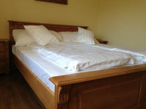 a large wooden bed with white sheets and pillows at Vida-lak in Berekfürdő