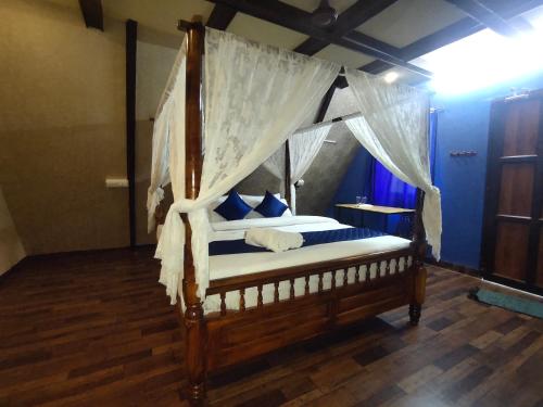 a bedroom with a canopy bed with blue pillows at PV Cottages - Serenity Beach in Puducherry