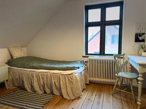 um quarto com uma cama, uma secretária e uma janela em JM B&B em Sakskøbing