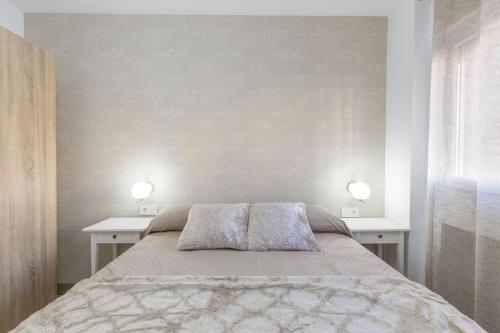ein Schlafzimmer mit einem Bett mit zwei Tischen und zwei Lampen in der Unterkunft Neptuno Deluxe in Granada