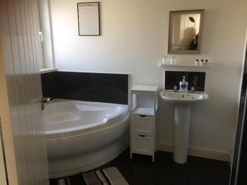 a white bathroom with a tub and a sink at Dha Urlar in Bowmore