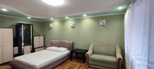 a bedroom with a bed and a chair at Уютная квартира возле CITY Mall in Zaporozhye