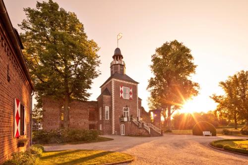 an old brick building with a tower on a street at Schloss Hertefeld & Hertefeldhof in Weeze