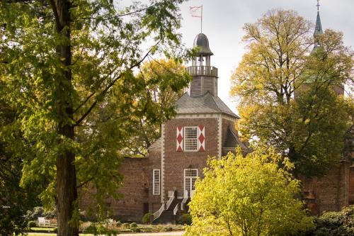 een oud bakstenen gebouw met een rood kruis erop bij Schloss Hertefeld & Hertefeldhof in Weeze