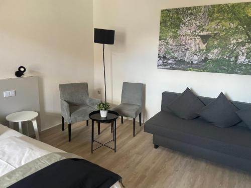a bedroom with a bed and a couch and chairs at Harzhotel Warnstedter Krug in Thale