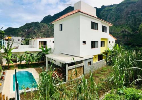 una casa blanca con montañas en el fondo en Residencial Lela d'Fermina en Pombas