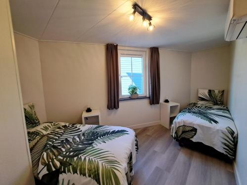 een slaapkamer met 2 bedden en een raam bij Apud nos Domi in Polsbroek