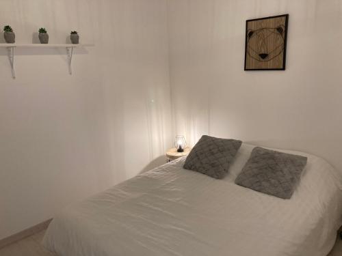 ein weißes Bett mit zwei Kissen darauf im Schlafzimmer in der Unterkunft Gîte Doumenc in Thierville-sur-Meuse