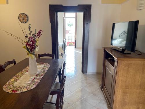 a dining room with a table and a tv on a cabinet at Casetta Parini in Porto Cesareo