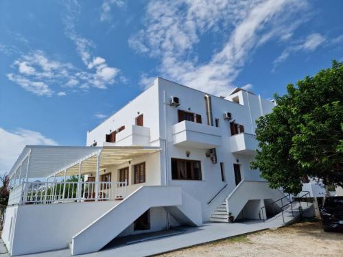 a white building with stairs and a blue sky at Afendra Hotel in Skiros