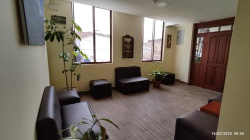 a living room with a couch and chairs and windows at Apart Cayambe in Cayambe
