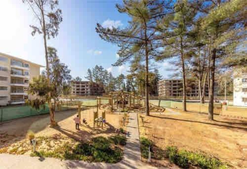 un parque infantil con árboles y edificios en Amplio depto en el Tabo 6 personas, en El Tabo