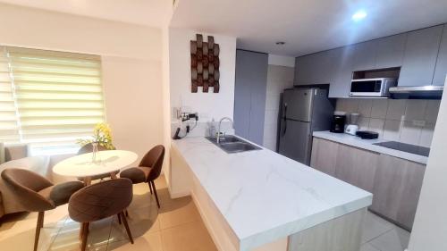 a kitchen with a white counter and a table and chairs at Suite Torre Sol OmniHospital Torre Médica in Guayaquil