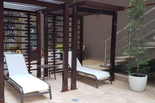 a pergola with white chairs on a patio at Suite Torre Sol OmniHospital Torre Médica in Guayaquil