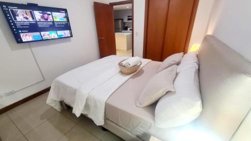 Un dormitorio con una cama blanca con una cesta. en Suite Torre Sol OmniHospital Torre Médica, en Guayaquil