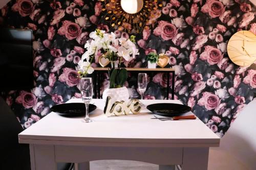 una mesa con dos vasos y una pared floral en ROMANTIC STUDIO EVE - PROCHE GARE - NETFLIX - WiFi, en Amiens