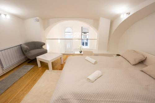 Duży, biały pokój z łóżkiem i krzesłem w obiekcie Parliament Exclusive Gallery w Budapeszcie
