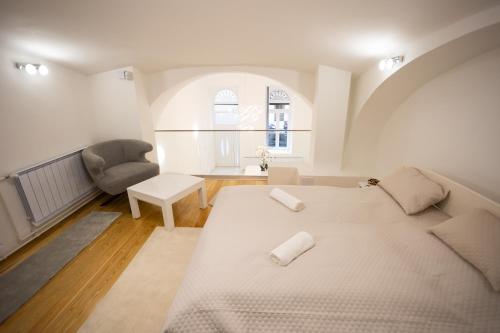 biała sypialnia z łóżkiem i krzesłem w obiekcie Parliament Exclusive Gallery w Budapeszcie