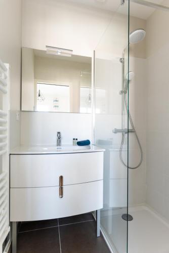 une salle de bain blanche avec un lavabo et une douche dans l'établissement Villa la plage, à Arcachon