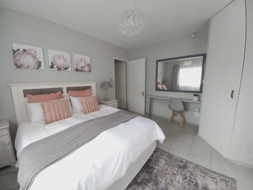 a bedroom with a large white bed with pink pillows at Silverdunes - GardenView in Bettyʼs Bay